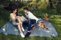 Young happy couple drinking red wine on a picnic in city park sitting on a blanket Royalty Free Stock Photo