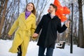 Young happy couple enjoy walking on winter street with red air balloons Royalty Free Stock Photo