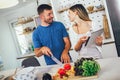 Happy couple is enjoying and preparing healthy meal in their kitchen and reading recipes on the digital tablet Royalty Free Stock Photo