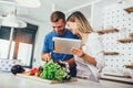 Happy couple is enjoying and preparing healthy meal in their kitchen and reading recipes on the digital tablet Royalty Free Stock Photo