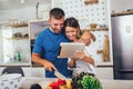 Happy couple is enjoying and preparing healthy meal in their kitchen and reading recipes on the digital tablet Royalty Free Stock Photo