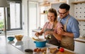 Young happy couple is enjoying and preparing healthy meal in their kitchen together Royalty Free Stock Photo