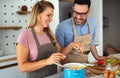 Young happy couple is enjoying and preparing healthy meal in their kitchen together Royalty Free Stock Photo