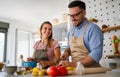 Young happy couple is enjoying and preparing healthy meal in their kitchen together Royalty Free Stock Photo