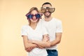 Young happy couple in funny party glasses on beige background