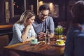 Young happy couple having coffee in cafe and looking at phone. Royalty Free Stock Photo