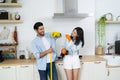 Young happy couple having fun while doing cleaning kitchen, They hold a mops and rags with spray bottle in hands Royalty Free Stock Photo