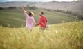 A young happy couple having fun while walking over a large meadow looking for a picnic spot. Love, relationship, together, nature Royalty Free Stock Photo