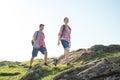 Young Happy Couple Hiking with Backpacks on the Beautiful Rocky Trail at Sunny Evening. Family Travel and Adventure. Royalty Free Stock Photo