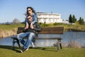 Young happy couple is hugging on a bench at the park. Royalty Free Stock Photo