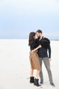 Young happy couple hugging in winter snow monophonic background, wearing skirt and black shirt.