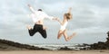 Young happy couple jumping for joy on beach Royalty Free Stock Photo