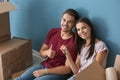 Young happy couple with key and moving boxes sitting on floor at new home Royalty Free Stock Photo