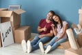 Young happy couple with key and moving boxes sitting on floor at new home Royalty Free Stock Photo