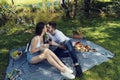Young happy couple kissing and drinking red wine on a picnic in city park sitting on a blanket near lake Royalty Free Stock Photo