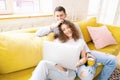 Young happy couple lies on a yellow sofa with a laptop in their apartment, online shopping and internet technology for home Royalty Free Stock Photo