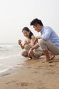 Young happy couple looking at seashell at the waters edge, China Royalty Free Stock Photo