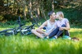 Young happy couple in love kissing. Walking in the park on bicyc