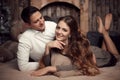 Young happy couple in love lying on rug in cozy wooden interior