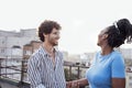 Young happy couple in love on roof of multi-storey building. Cute curly-haired interracial guy holds hand of charming African Royalty Free Stock Photo