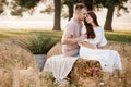 young happy couple in love sitting on straw stack in summertime in the park. Man and woman hugging, sunlight in summer Royalty Free Stock Photo