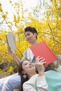 Young happy couple lying and sitting on a park bench enjoying reading their books, outdoors in springtime Royalty Free Stock Photo