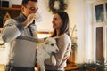 Young happy couple man and woman holding cute white dog and hugging while standing in kitchen decorated for Christmas Royalty Free Stock Photo