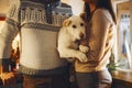 Young happy couple man and woman holding cute white dog and hugging while standing in kitchen decorated for Christmas Royalty Free Stock Photo