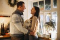 Young happy couple man and woman holding cute white dog and hugging while standing in kitchen decorated for Christmas Royalty Free Stock Photo