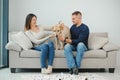 The young happy couple is moving into a new house. They are sitting down on the floor with their little puppy after they brought Royalty Free Stock Photo