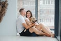 The young happy couple is moving into a new house. They are sitting down on the floor with their little puppy after they brought Royalty Free Stock Photo