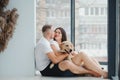 The young happy couple is moving into a new house. They are sitting down on the floor with their little puppy after they brought Royalty Free Stock Photo