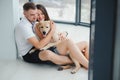 The young happy couple is moving into a new house. They are sitting down on the floor with their little puppy after they brought Royalty Free Stock Photo