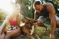 Young happy couple playing with their dog smiling in park Royalty Free Stock Photo