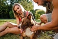 Young happy couple playing with their dog smiling in park Royalty Free Stock Photo