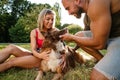 Young happy couple playing with their dog smiling in park Royalty Free Stock Photo