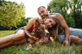 Young happy couple playing with their dog smiling in park Royalty Free Stock Photo