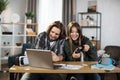 Young happy couple playing video games at home, sitting at the table with laptop and using joysticks Royalty Free Stock Photo