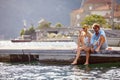 A young happy couple is relaxing with the drink while sitting on the dock on the seaside with their legs in the water. Love, Royalty Free Stock Photo