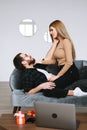 Young happy couple resting on a sofa at home gently touching each other Royalty Free Stock Photo