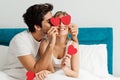 Young happy couple sitting on the bed, holding hearts Royalty Free Stock Photo