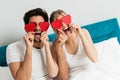 Young happy couple sitting on the bed, holding hearts Royalty Free Stock Photo