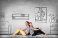 Happy couple sitting on the floor among painted furniture on the wall. Royalty Free Stock Photo