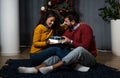 Young happy couple sitting at home in front of the Christmas tree decorated with decorations exchanging gifts for the New Year Royalty Free Stock Photo