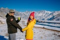 Young happy couple in snowy mountains with copy space. Guy and girl in bright clothes holding hands looking at camera and smiling Royalty Free Stock Photo