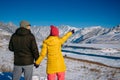 Young happy couple in snowy mountains with copy space. Guy and girl in bright winter clothes look at the snowy peaks. Christmas Royalty Free Stock Photo