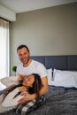 Young happy couple spending time at home, sitting on bed in cozy renovated apartment, laughing, having fun Royalty Free Stock Photo