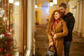 A young happy couple stand on the street looking at the Windows in the evening