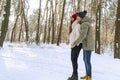 Young happy couple are standing and hugging on sunny day in snow-covered park. Men and women in a snowy winter park. Side view Royalty Free Stock Photo