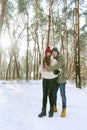 Young happy couple are standing and hugging on sunny day in snow-covered park. Portrait of men and women in a snowy winter park. Royalty Free Stock Photo